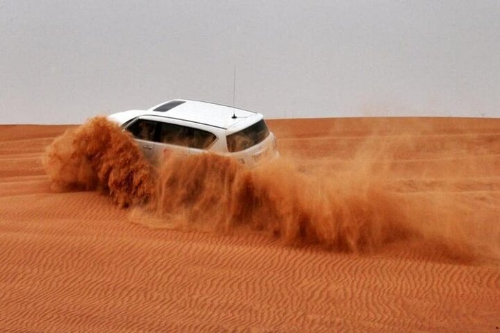Ride over the stunning red sands of Dubai feeling the rush of adventure as your 4×4 navigates the dunes leading to unforgettable sunset views and desert experiences.
